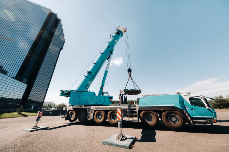 the counterweight is installed by an unrecognizable worker on a large blue car crane and is prepared to work on a site next to a large modern building. The largest truck crane for solving complex tasks. the counterweight is installed by an unrecognizable worker on a large blue car crane and is prepared to work on a site next to a large modern building. The largest truck crane for solving complex tasks